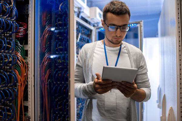 Hombre revisando una tablet en una sala de servidores