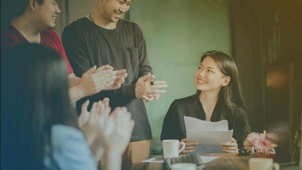 Compañeros de una empresa aplaudiendo a una empleada